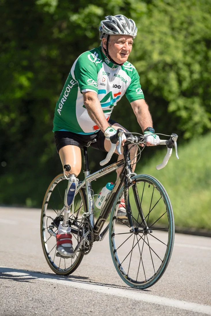A cyclist riding outdoors on a lower-limb prosthesis.